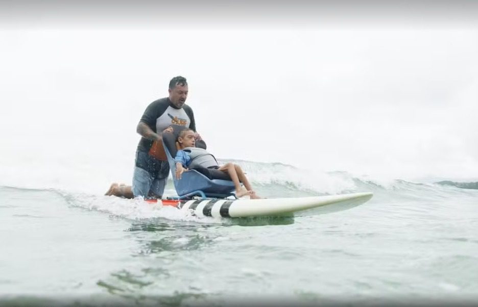 Pais criam prancha de surfe adaptada para filho com paralisia se aventurar no mar: ‘Tudo pela felicidade dele’